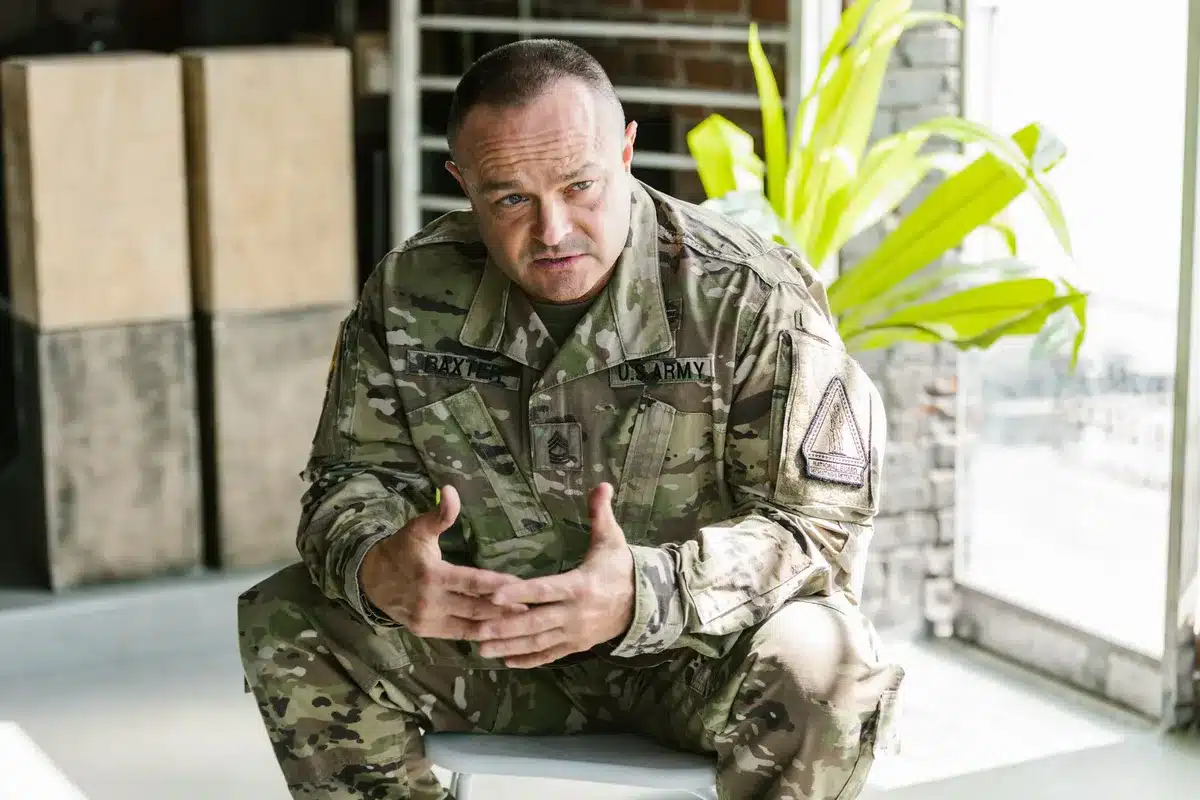 Army general's dress uniform with four gold stars visible on shoulder board, crisp pressed fabric under bright institutional lighting, professional military bearing suggested by posture and detail, authority and tradition.