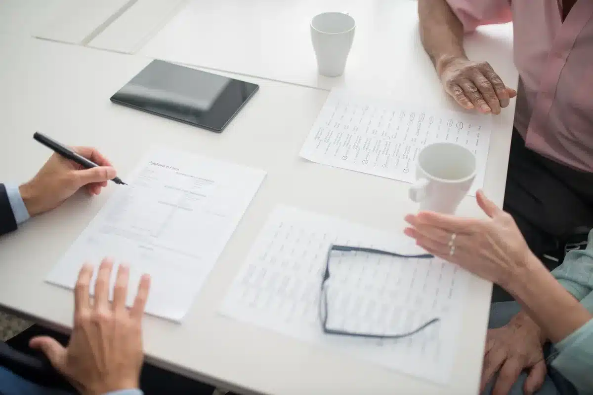 A conference room table with empty chairs, papers and legislative documents scattered, a single coffee cup, representing the intensive work sessions ahead.
