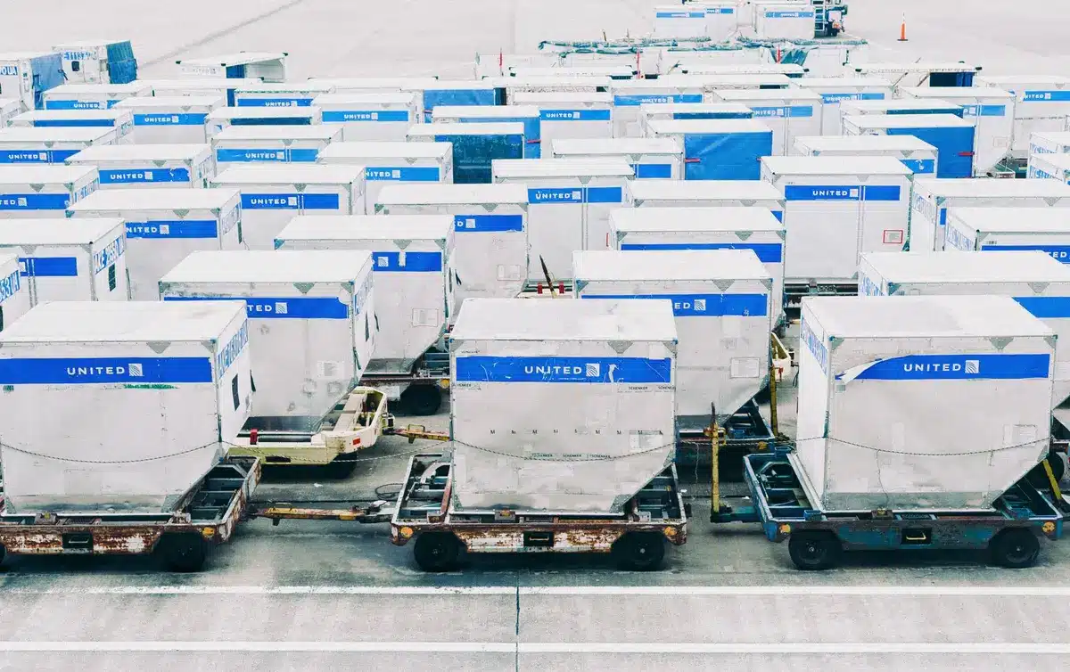 A modern airport security checkpoint with uniformed personnel and detection equipment, representing heightened security protocols. Soft focus background shows aircraft hangars and tarmac. No identifiable individuals.