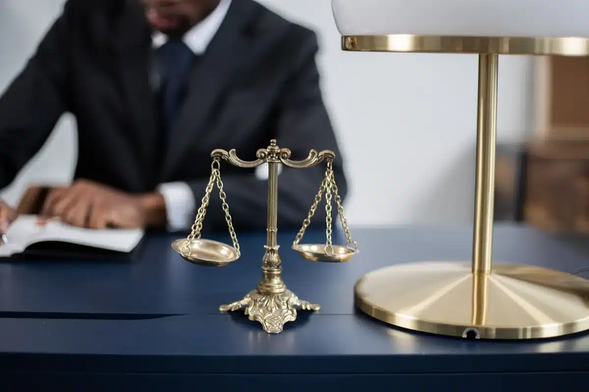 Law books and gavel on a wooden desk in dim courtroom lighting, representing legal proceedings