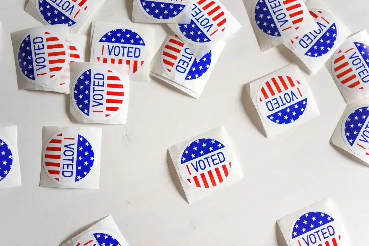 Democratic primary voting location with ballot boxes and campaign materials, voters entering polling booths