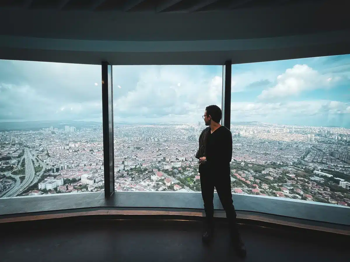 An observation cupola with glass barriers offering panoramic city views, visitors silhouetted against sweeping skyline vistas, warm afternoon light flooding the 36th-floor space.