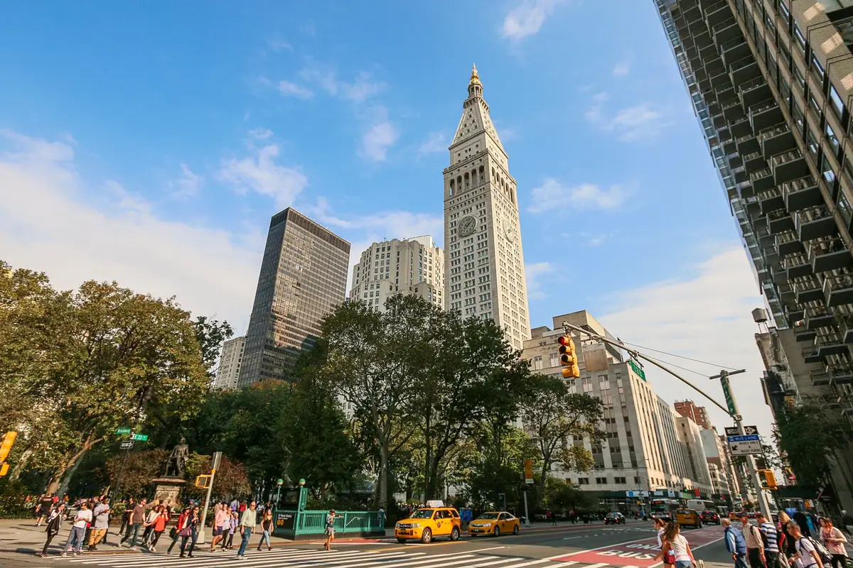 The historic David N. Dinkins Municipal Building exterior at 1 Centre Street, Beaux-Arts facade catching late-afternoon light, the distinctive cupola silhouetted against the Manhattan skyline.