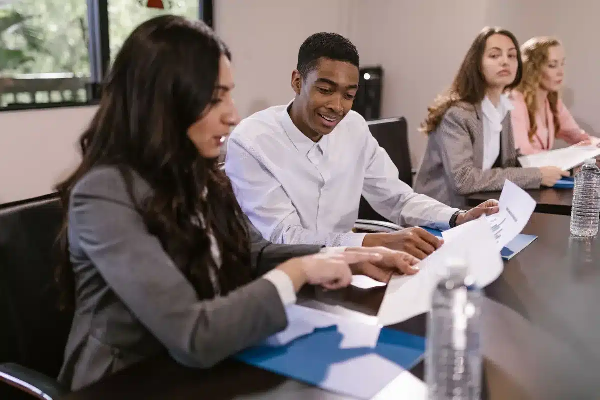 A diverse group of anonymous professionals in business attire sitting around a conference table, engaged in discussion, faces obscured or turned away, representing judicial appointment deliberations without identifying any individual.