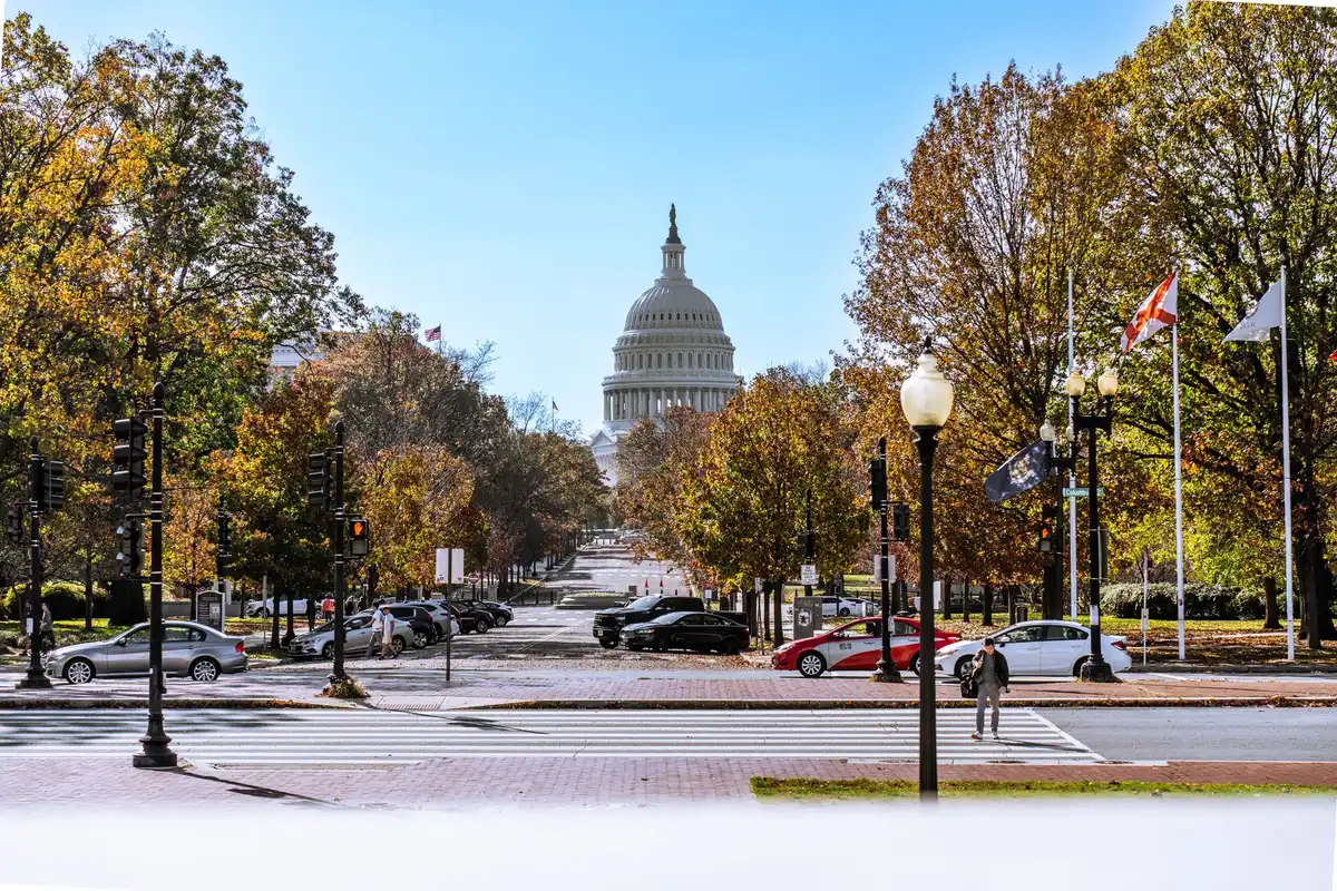The U.S. Capitol building exterior in daylight, Senate chamber doors visible, American flags flying, solemn government architecture