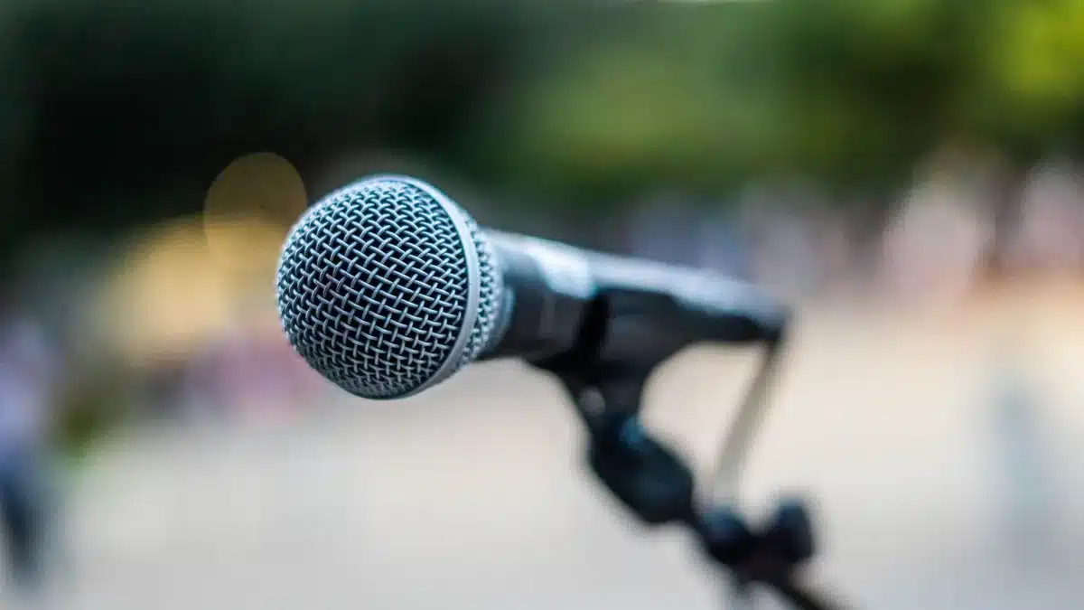 A split-screen showing a podium microphone under bright stage lights on one side and an empty debate stage on the other, representing the final campaign stretch before voting