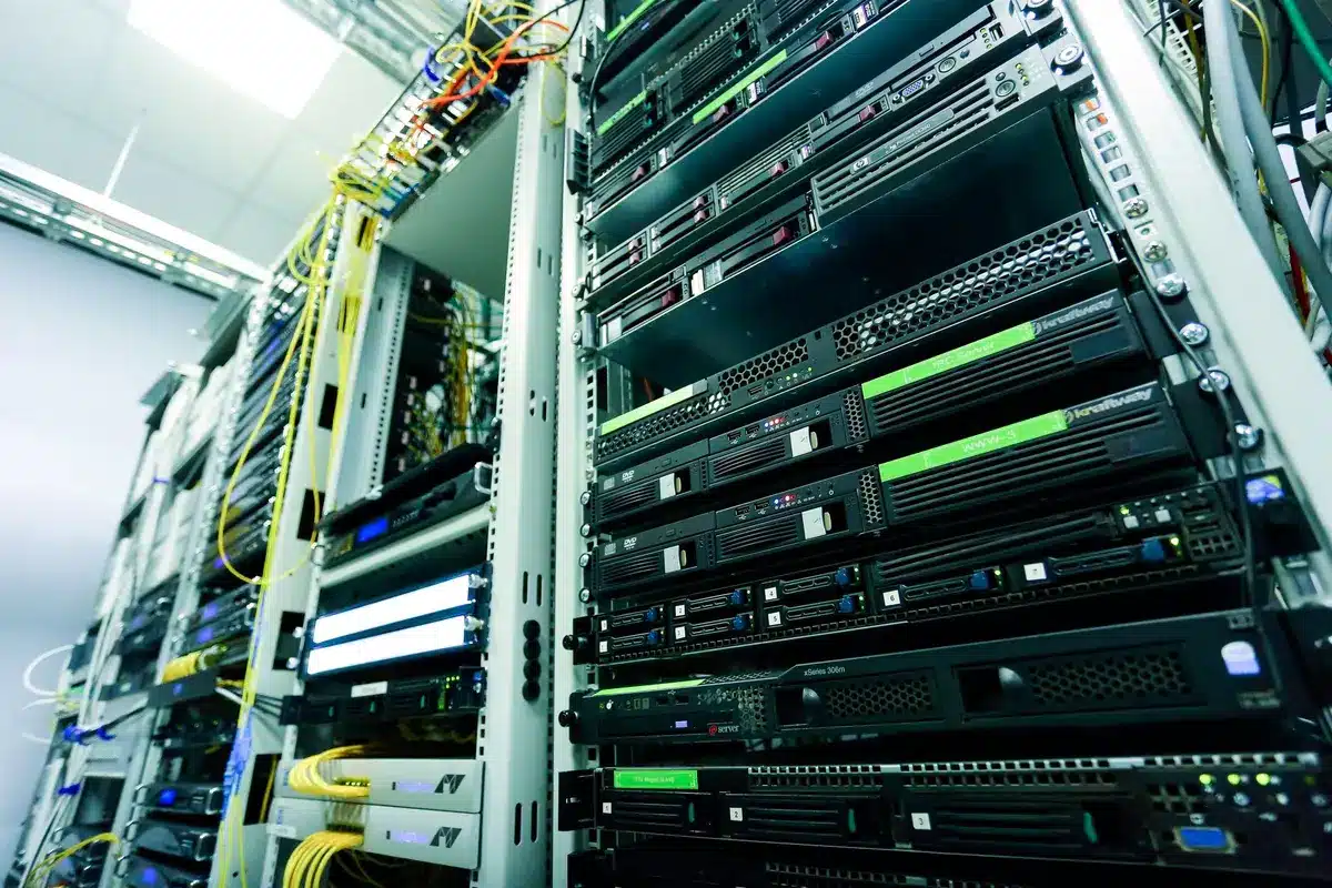 A modern data center filled with rows of glowing server racks, blue and green indicator lights illuminating the facility, conveying the infrastructure backbone of AI systems.