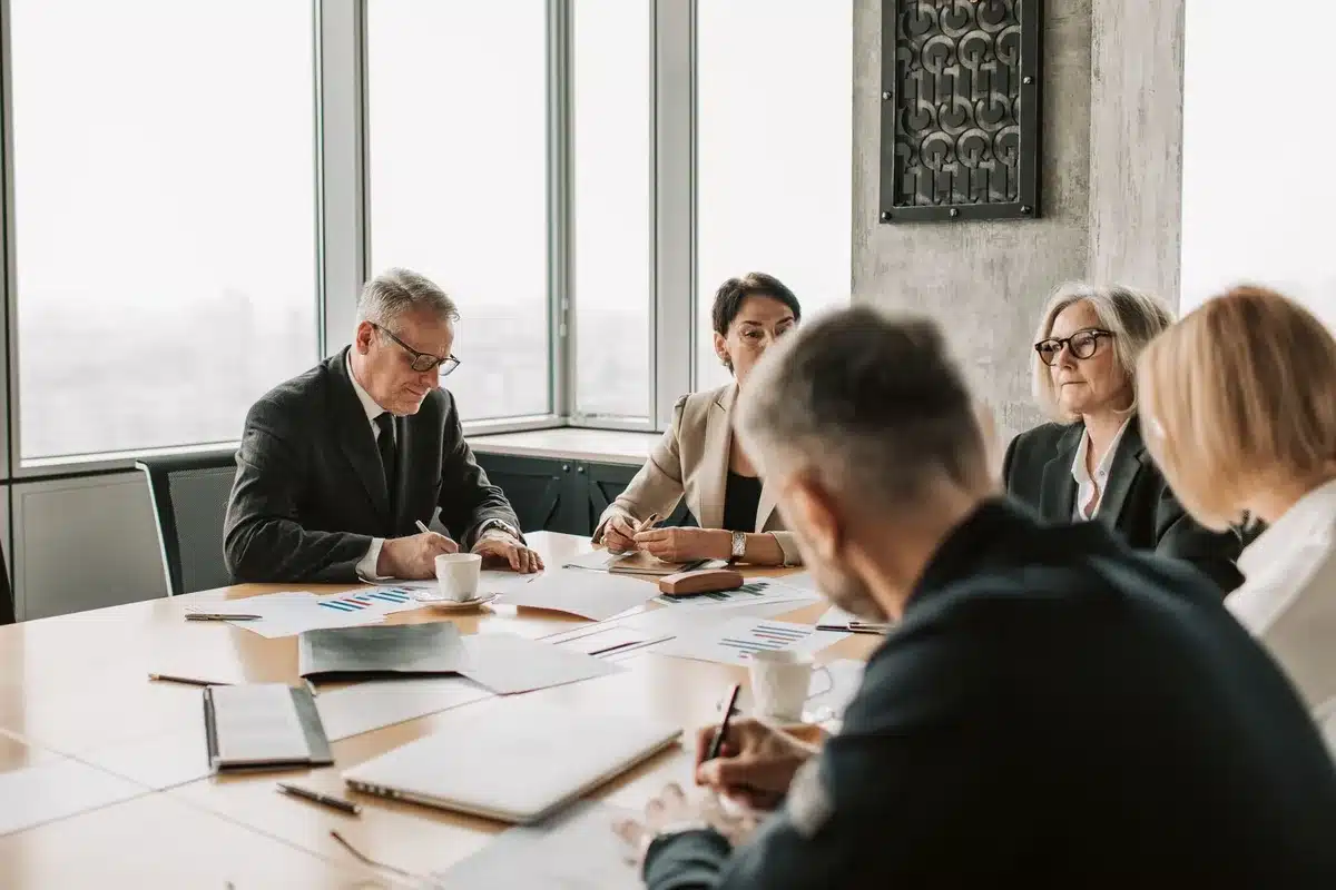 A corporate boardroom with large screens displaying financial charts and growth projections, an empty executive chair facing the screens, soft lighting reflecting off glass surfaces, representing long-term strategic planning and ambition
