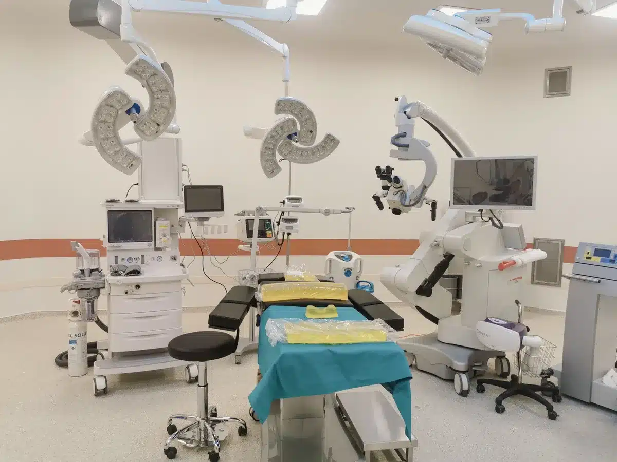 A hospital corridor with rehabilitation equipment visible, fluorescent lighting casting shadows on empty beds, suggesting recovery and medical treatment in progress