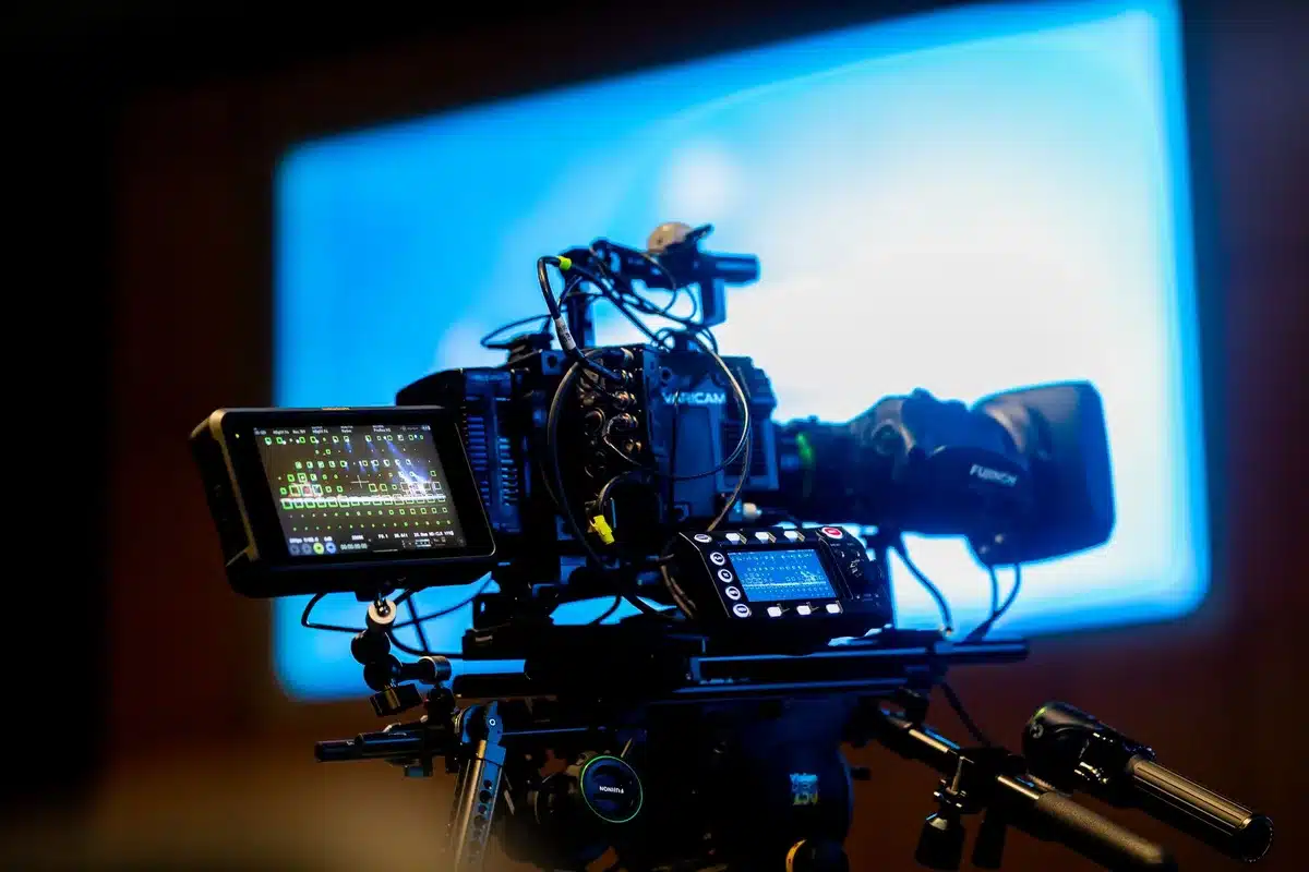 A film production set with archival cameras, reels of film stock, and editing equipment arranged on a studio table, warm lighting highlighting preserved footage materials.