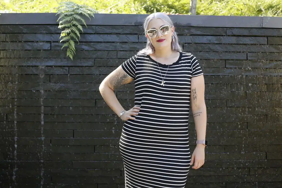 A striped summer dress in ivory and racing-green displayed on a simple white background, the fabric catching light to show texture and movement, evoking refined vacation style