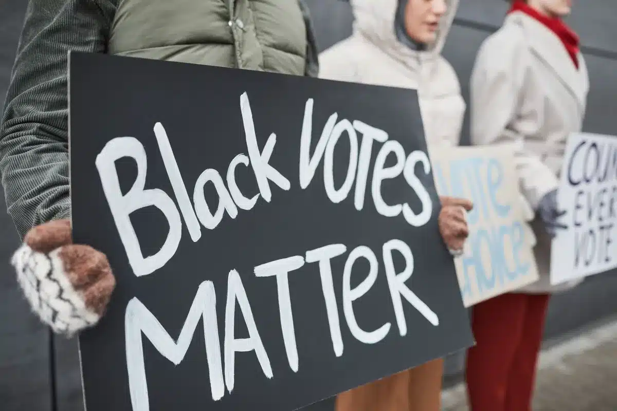 Two anonymous campaign signs in contrasting colors representing progressive and moderate political philosophies, positioned side by side in a Michigan community setting