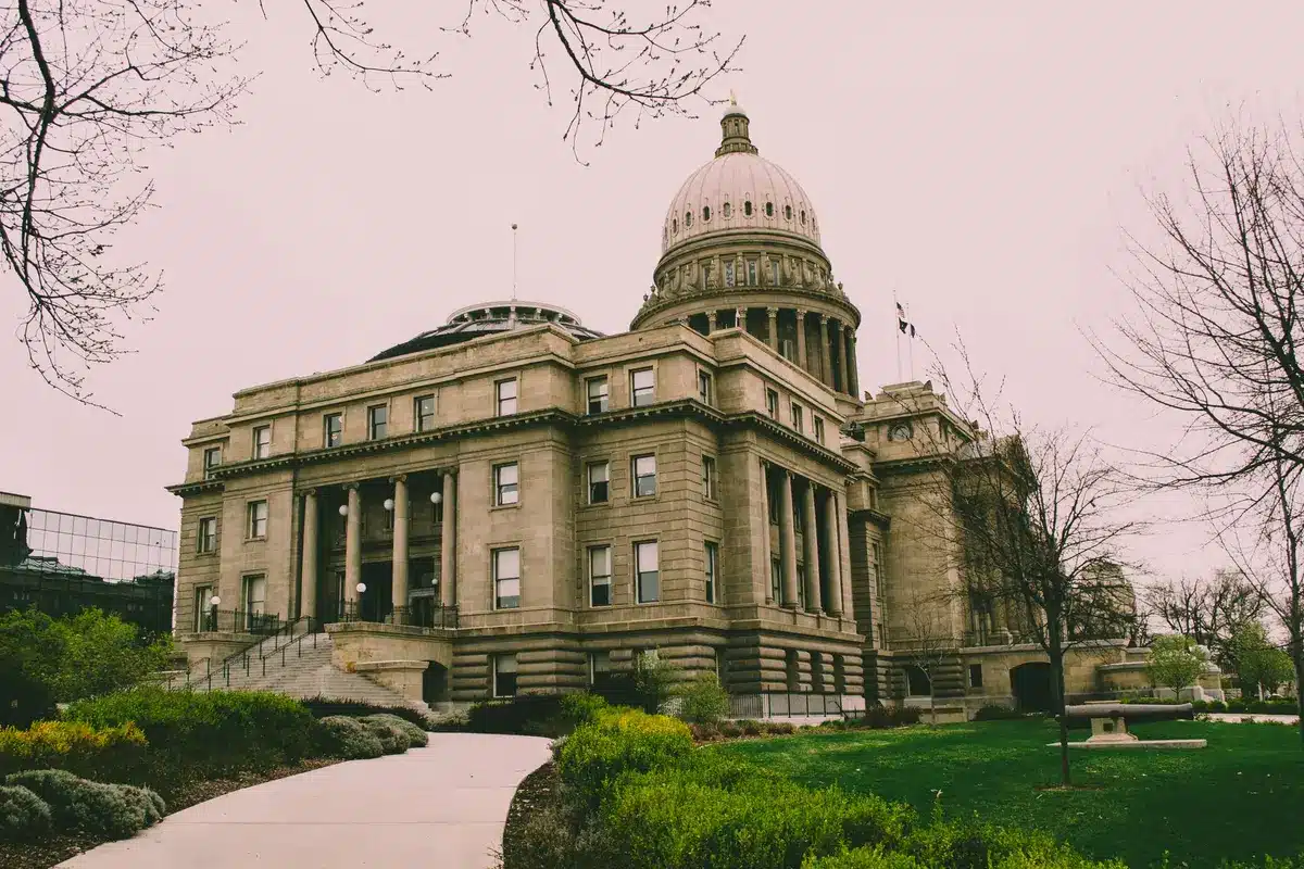 A modern state capitol building exterior at dusk, Michigan flag flying, empty legislative chamber visible through lit windows, symbolic of the executive power being contested