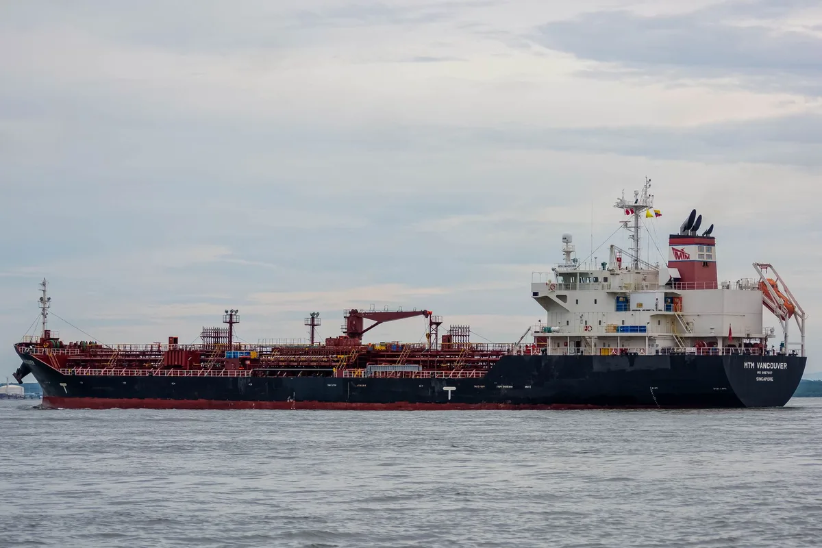Commercial oil tankers lined up in calm waters of a major shipping lane, with clear horizon and minimal traffic, symbolizing the reopening of vital maritime corridors