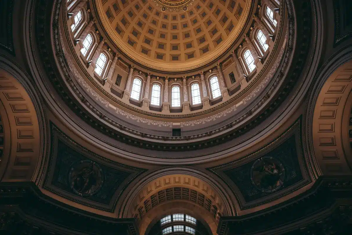 A Minnesota state capitol building dome silhouetted against a twilight sky, with flags at half-mast, suggesting the transition of political power and governance.