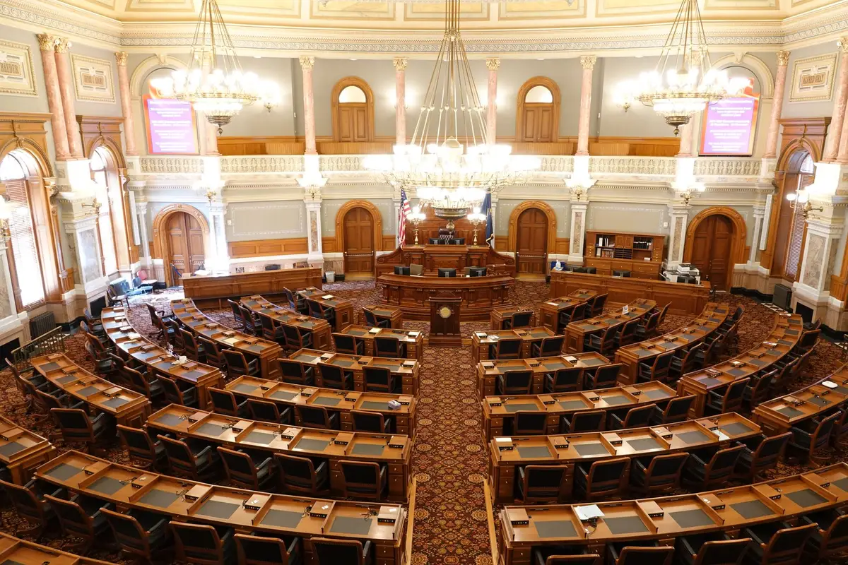 A split-screen view showing two empty podiums on a stage, one bathed in warm light and one in cool light, symbolizing the two candidates awaiting their November matchup
