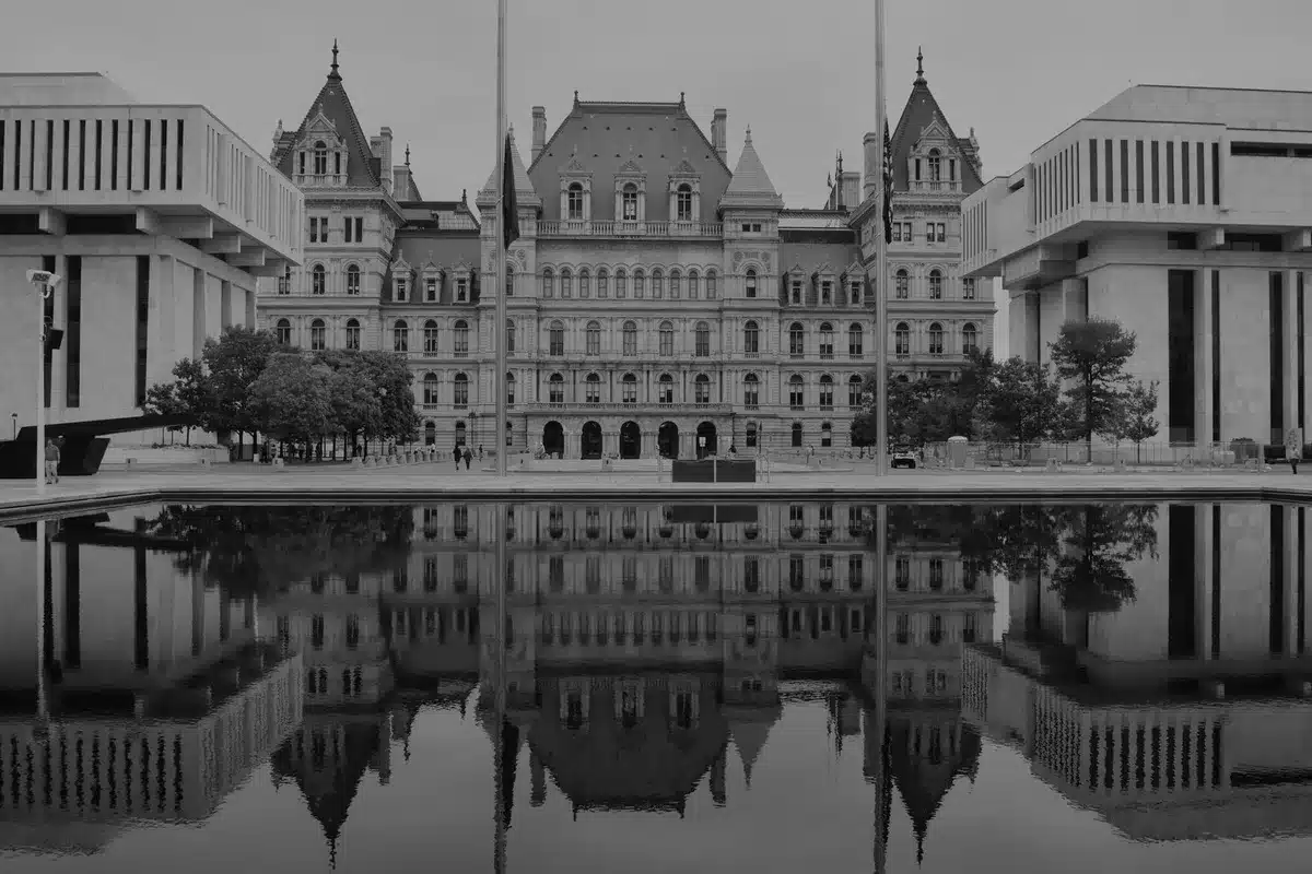 A state capitol building exterior at dusk with election signage visible, voters walking toward the entrance