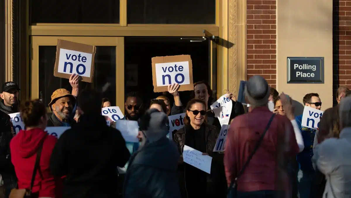 A diverse group of citizens holding "vote no" signs outside a polling location, morning light | protest sign voting poll
