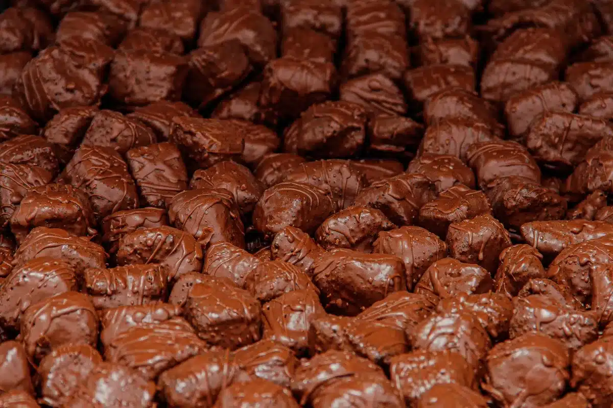 Colorful candy pieces in mint and brown tones, close-up macro view of individual M&amp;M's with visible cookie texture center, bright studio lighting