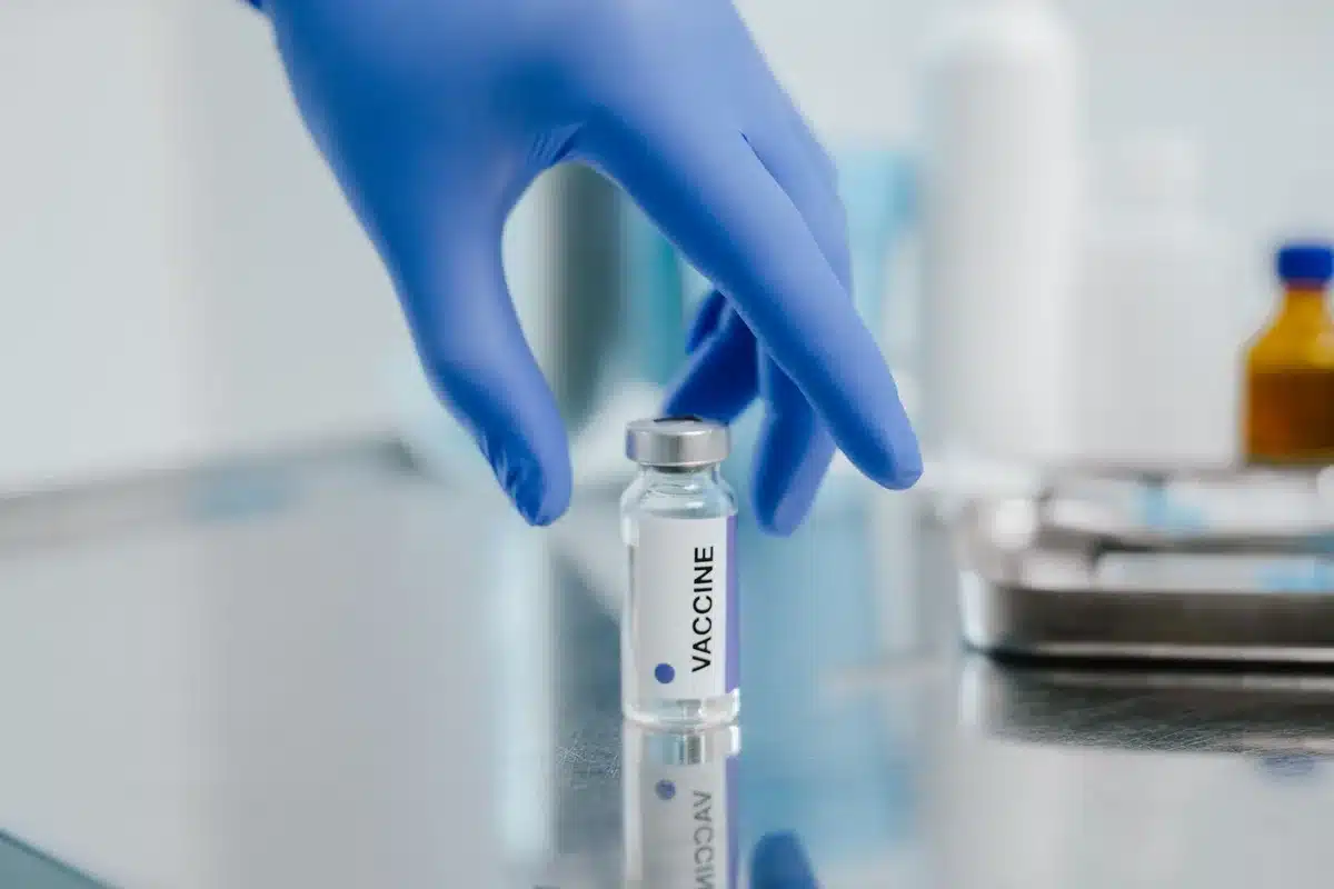 Modern laboratory workbench with vaccine vials under soft lighting, sterile environment visible, clinical precision evident