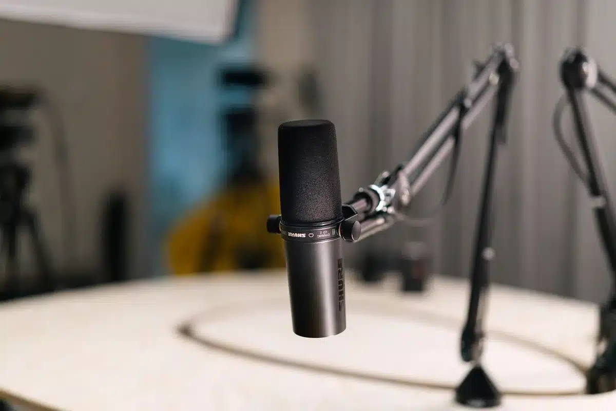 Microphone in spotlight on empty podcast studio set, soft lighting and shadow, professional audio equipment visible