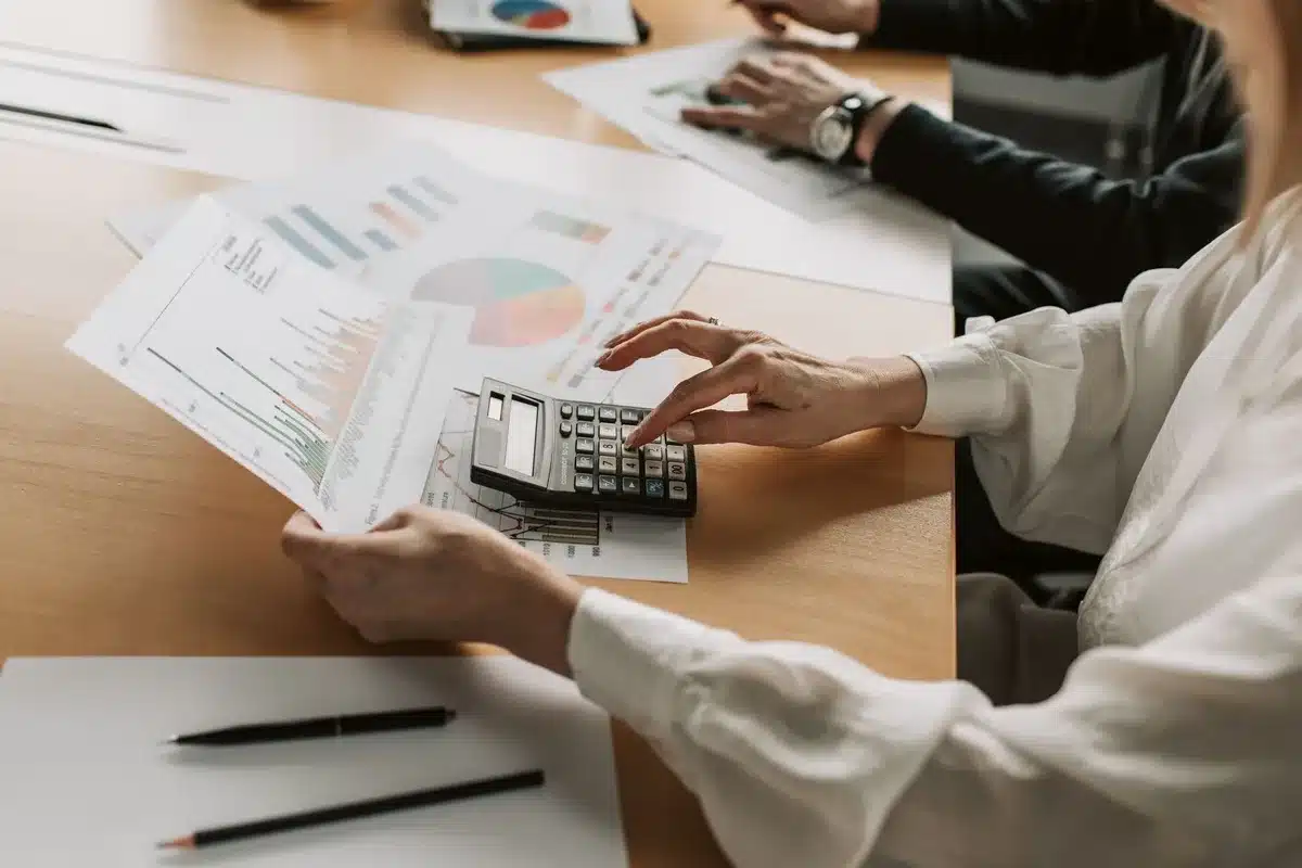 A printed mortgage document with a calculator and pen on a desk, next to a chart showing interest rate trends over time