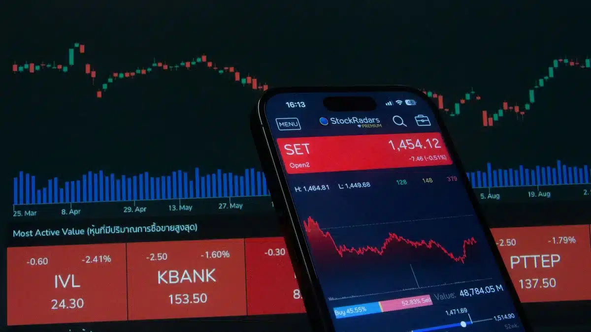 Stock market analysis charts and data visualizations displayed on a glowing monitor screen in a professional trading environment, showing upward trend lines and portfolio performance metrics