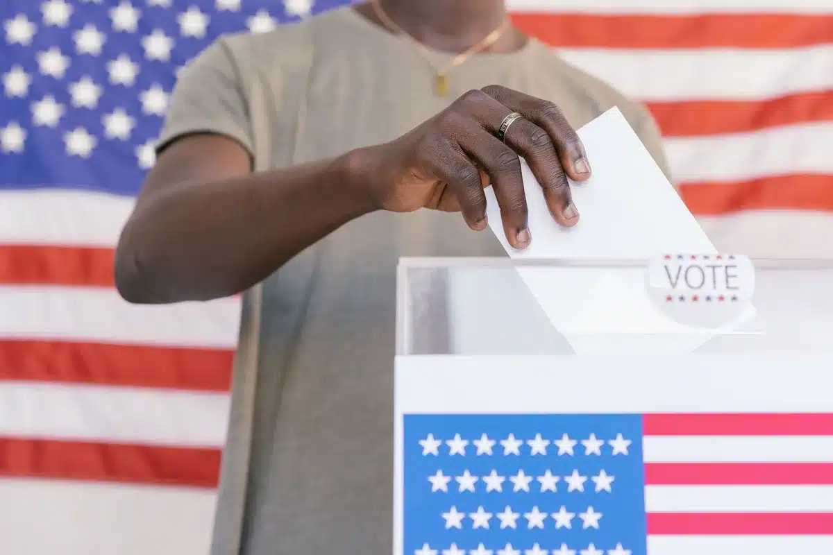 A diverse group of voters entering a community polling place at a local school gymnasium, some holding identification documents.