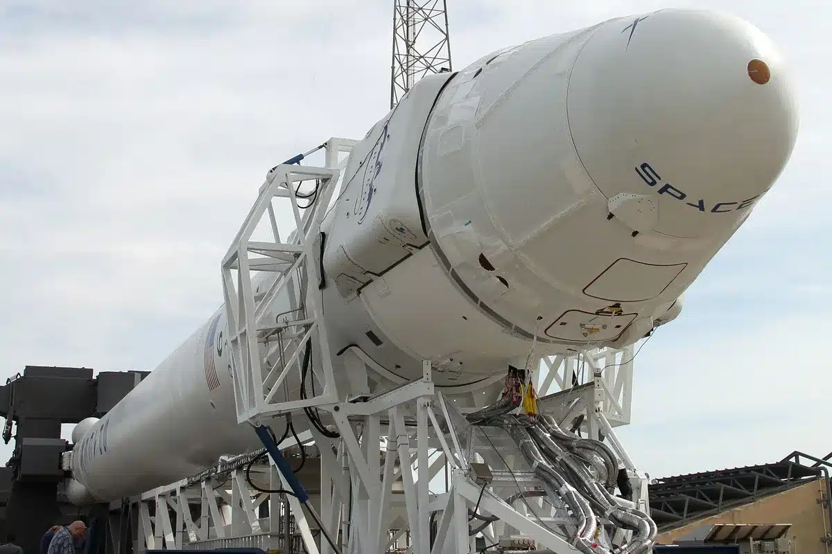 A Falcon Heavy rocket on a launch pad at dawn, with the Atlantic Ocean visible in the background and a clear sky overhead, ready for ignition.