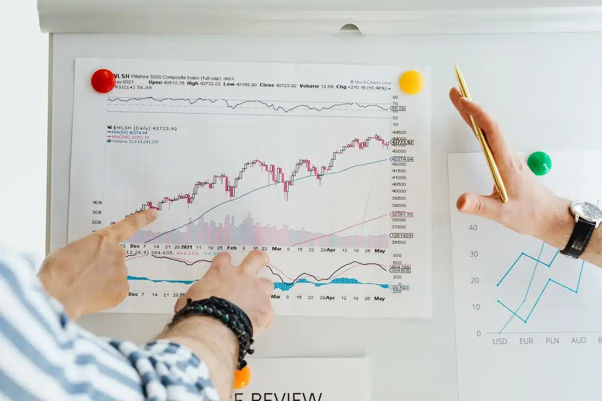 Computer screens showing stock market data and AI-related company names in red, with financial charts declining, reflecting tech sector volatility