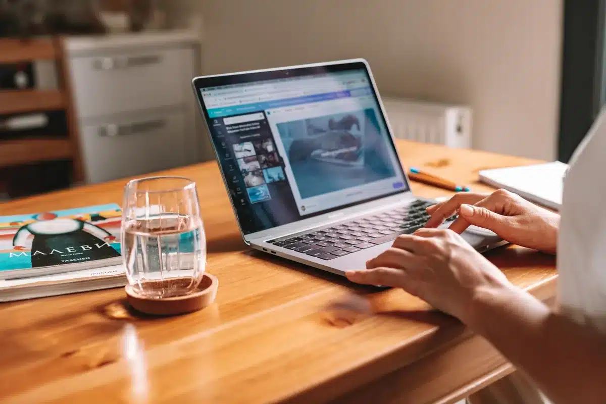An open laptop displaying a donation page with a glowing donate button, hands poised above the keyboard, warm screen light illuminating the workspace