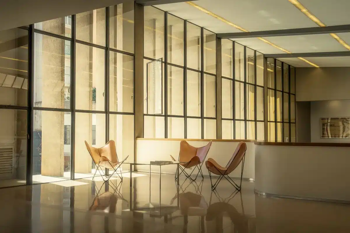Empty diplomatic conference room with two chairs facing each other across a table, one chair vacant, soft lighting, symbolic of stalled negotiations