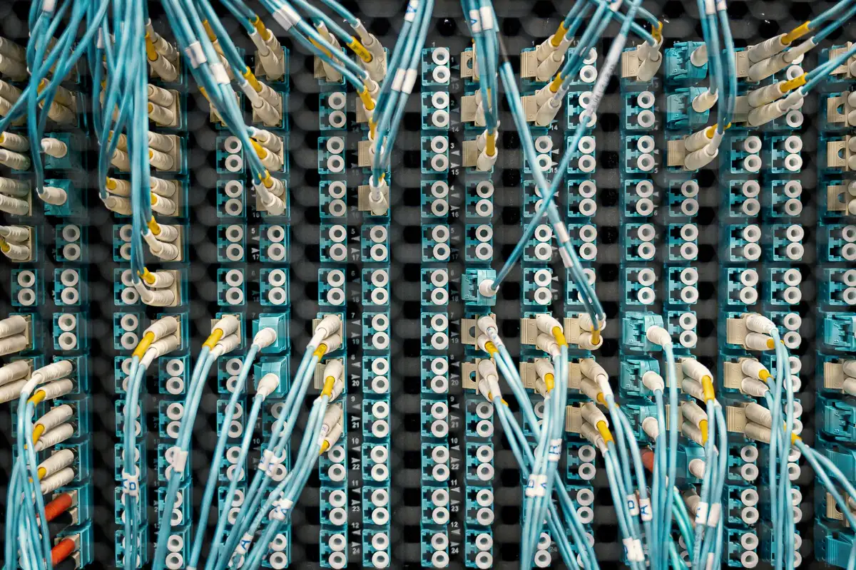 Glowing server towers in a data center, blue and white LED lights illuminating rows of hardware stacked floor to ceiling, with soft focus cables and cooling systems visible
