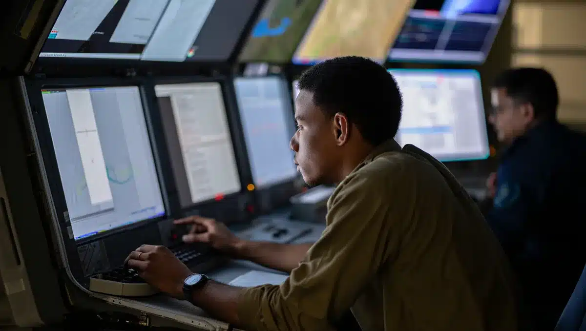 Autonomous defense systems control station with multiple screens displaying tactical data, hands on controls, focused concentration on mission operations | defense technology operations center