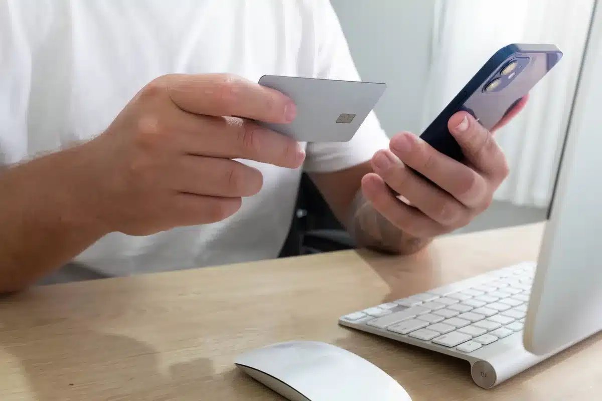 A close-up of hands holding a smartphone displaying a secure payment confirmation screen, with a blurred background of a real estate office or title company workspace, warm ambient lighting, subtle depth of field.