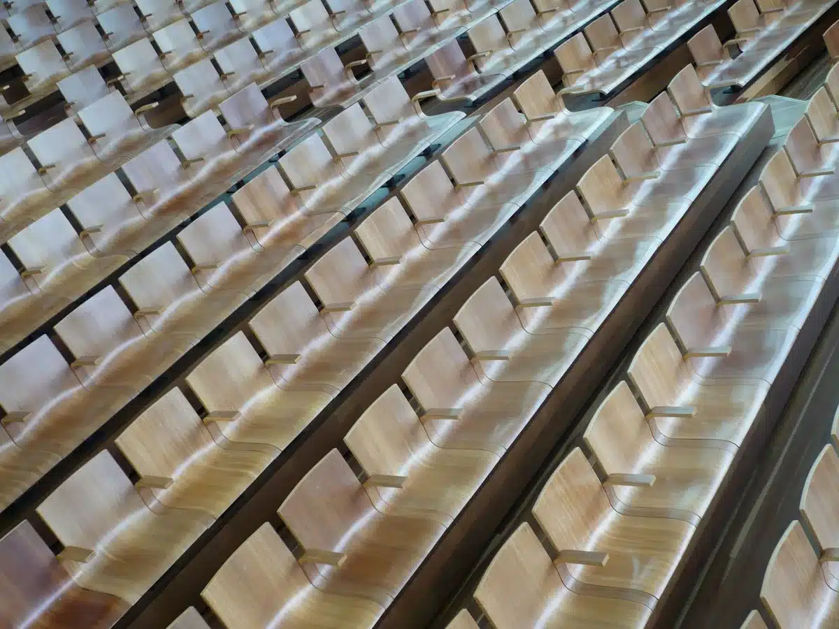 An empty legislative chamber or congressional hearing room with rows of seats facing a central podium, symbolizing the stakes for Congress