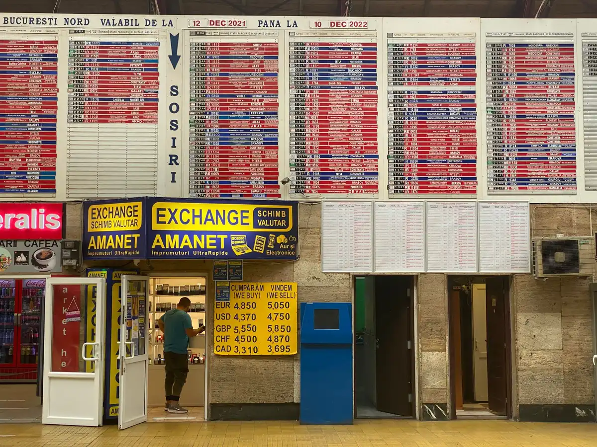A currency exchange board displaying peso-to-dollar rates, with glowing digital numbers updating in real time against a blurred urban background, capturing the dynamic nature of currency markets.