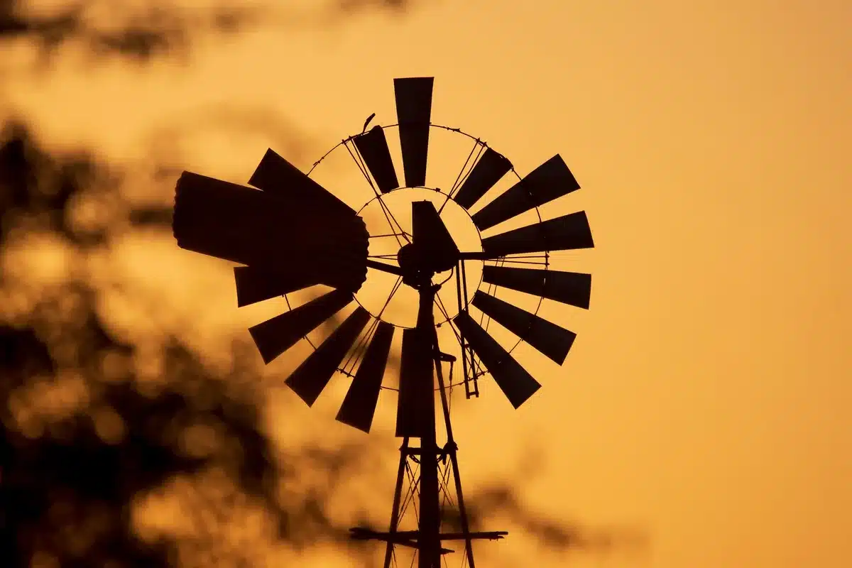 Historic photograph of early 1920s wind turbine technology next to modern turbine blade, sepia and color contrast
