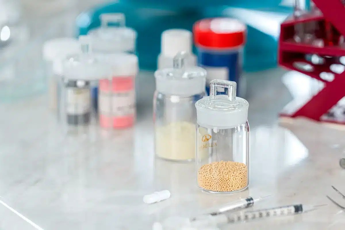 A pharmaceutical laboratory workspace with multiple vials and medical equipment arranged on a clean white surface, representing drug development and manufacturing.