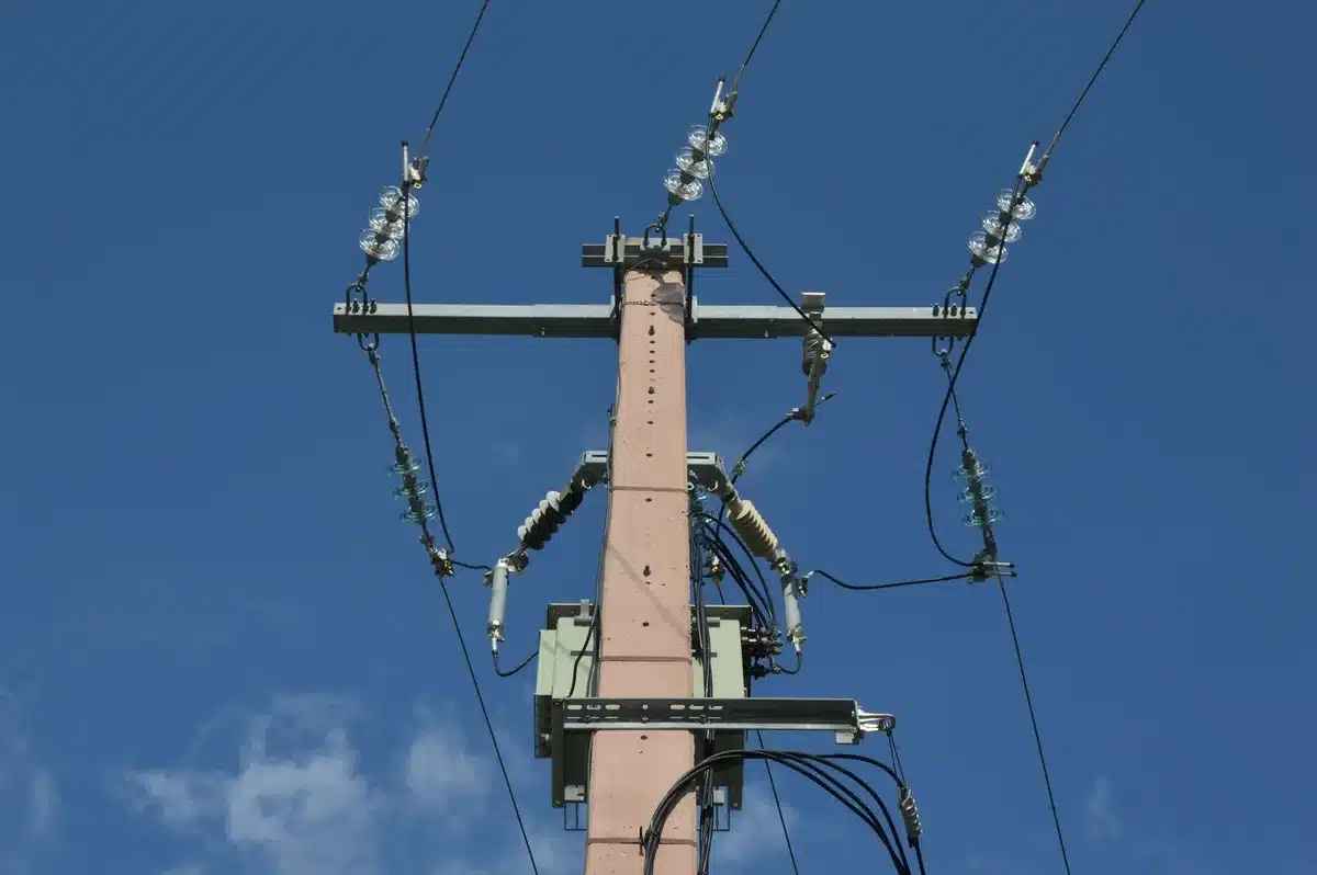 A sprawling electrical substation with towering transmission towers and high-voltage equipment under overcast sky, showing interconnected power lines and transformers at a critical grid junction.