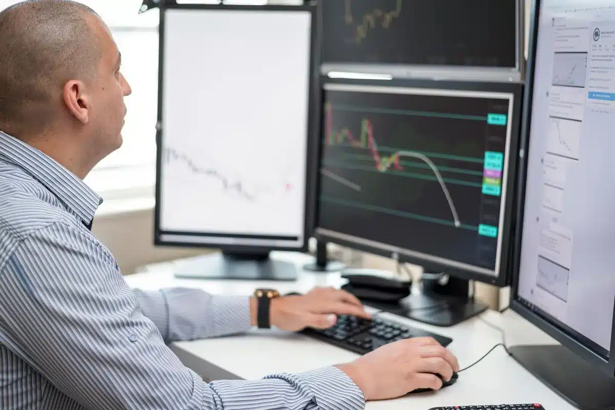 Empty trading floor with monitors displaying flat price lines, desks with scattered financial documents, dim overhead lighting casting shadows, a sense of pause and uncertainty in market activity