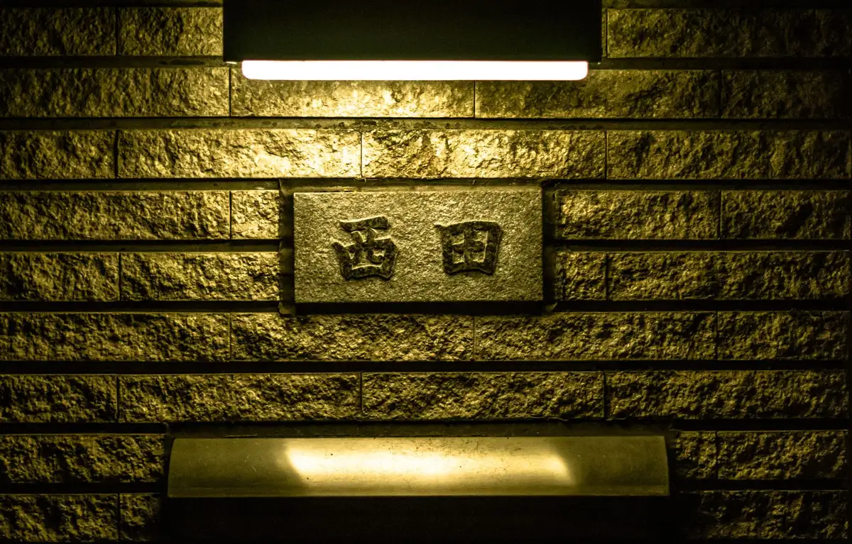 Multiple framed press credentials hanging on a wall, a nameplate reading "Press Secretary" being removed, soft shadow cast across the surface, morning light, the empty hooks where it hung