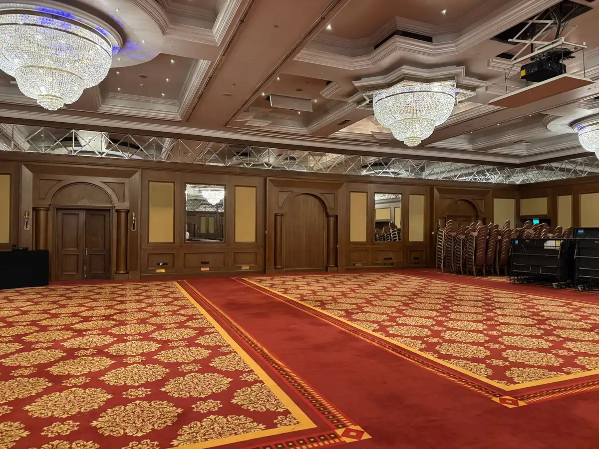 A dimly lit conference room with empty chairs facing each other across a polished table, a single microphone centered, suggesting high-stakes diplomatic negotiations