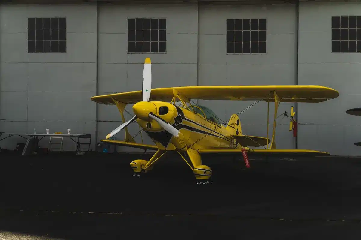 Maintenance technicians working on aircraft engine in hangar with tools and equipment visible