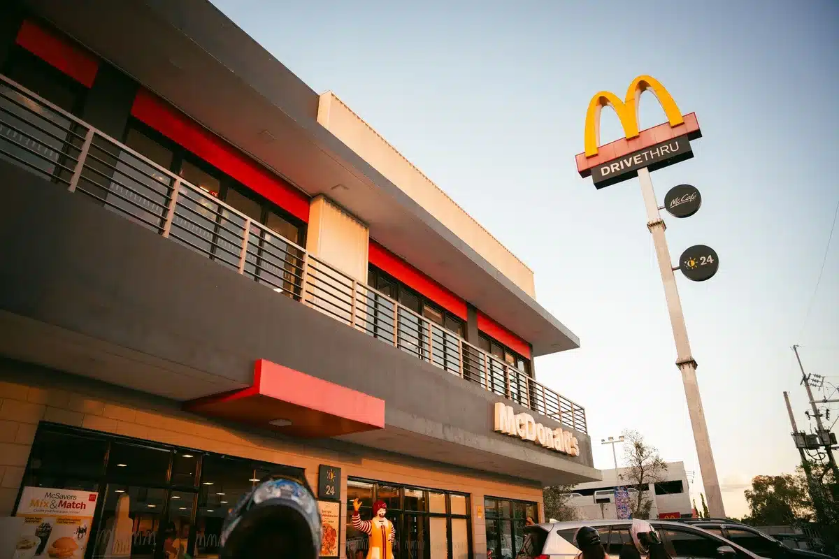 Row of restaurant locations at night with illuminated signage and storefront windows, multiple unit interiors visible through glass, diverse architectural styles, suburban and urban settings mixed