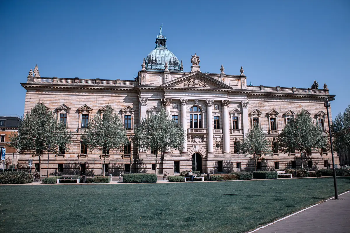 A federal courthouse entrance with stone columns and steps, morning light, empty plaza in front, symbolizing the legal judgment that triggered the bankruptcy filing.