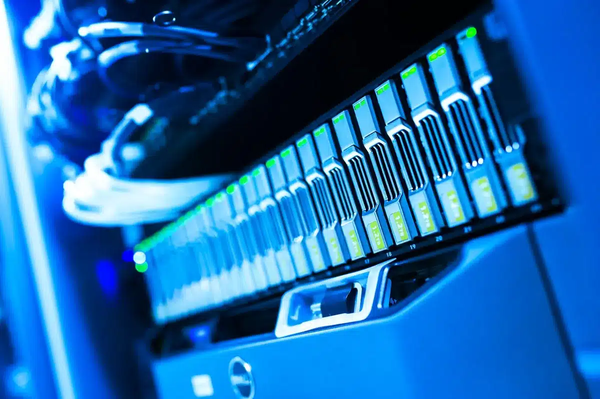 Server room with rows of networked computers and cables, cool blue lighting, data flowing across screens, abstract representation of digital infrastructure and compliance systems