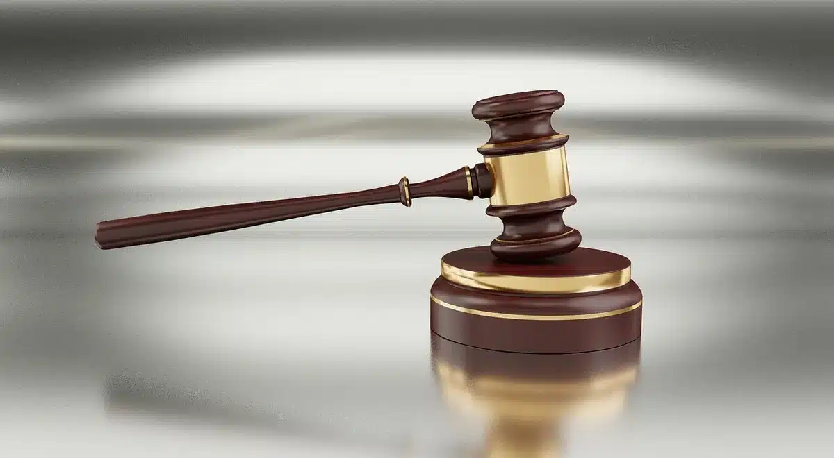 Law books on a shelf with a gavel resting on top, courtroom library setting, soft focus background