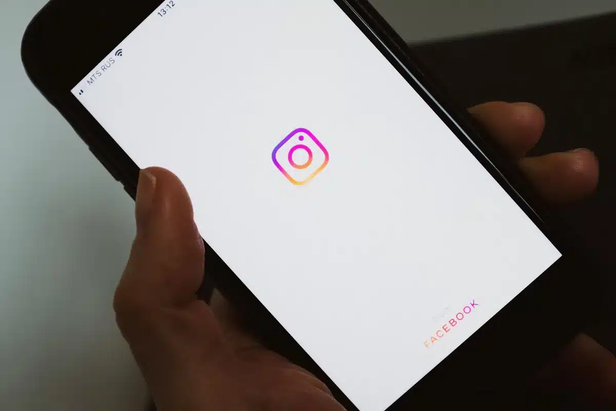 A close-up of hands holding a smartphone displaying social media content, with soft natural light filtering across the screen.