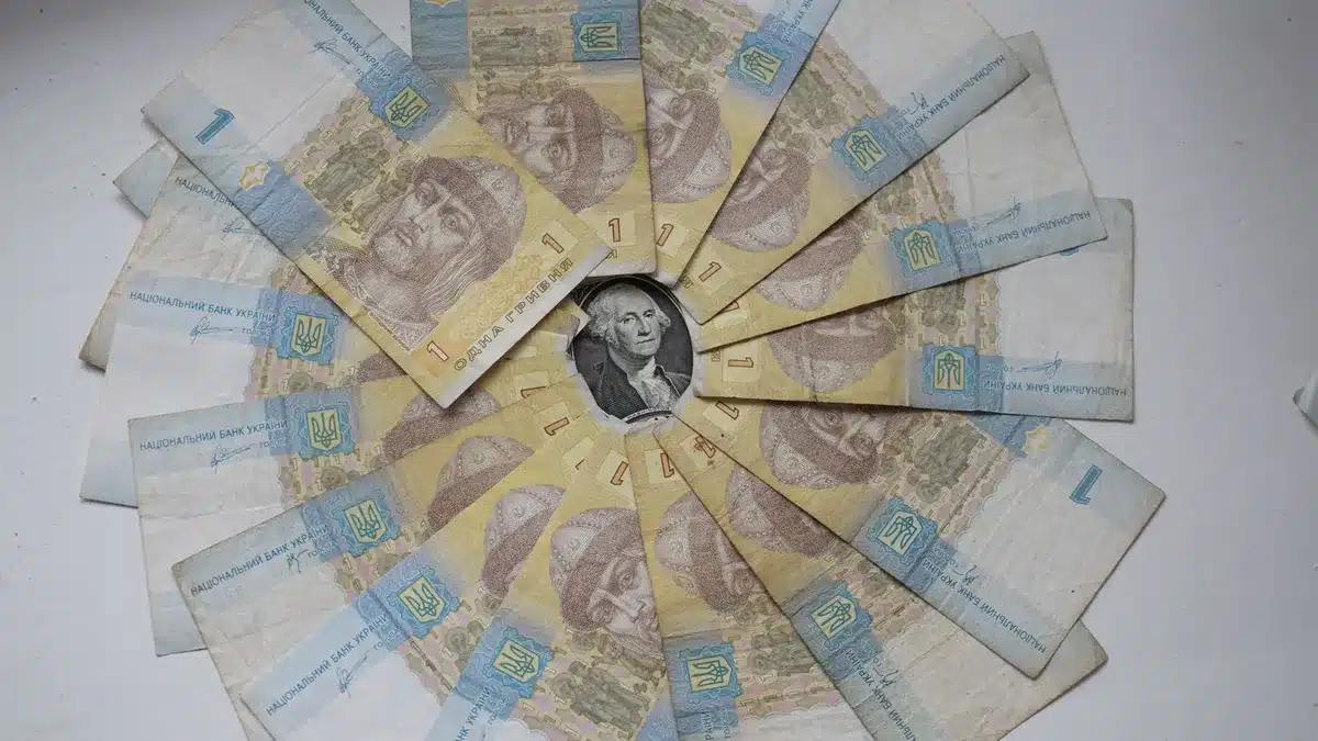 A close-up of Russian ruble banknotes fanned out on a wooden surface, with blurred background suggesting a home interior, emphasizing the physical currency rather than digital banking.